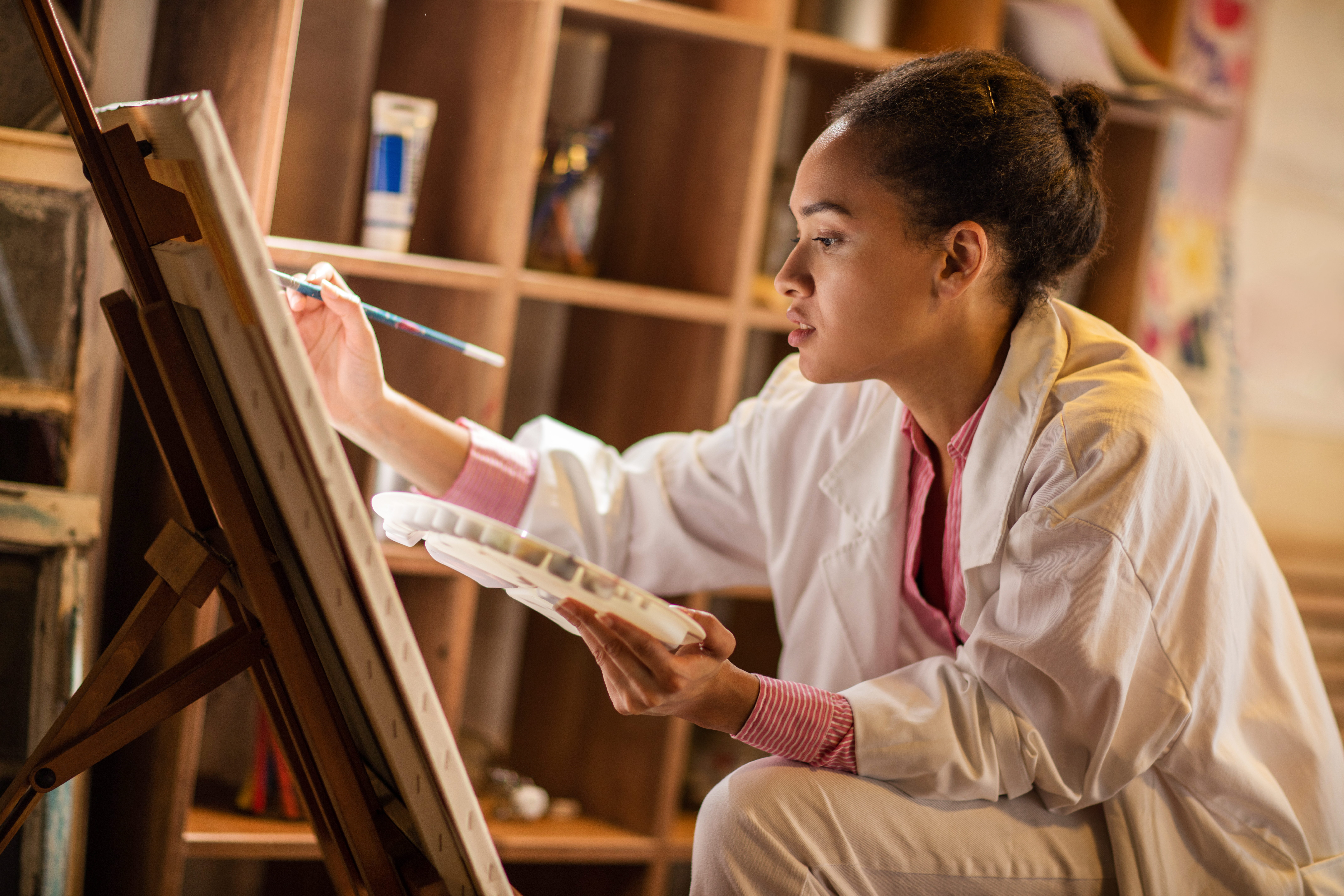Young African American painter working in her studio.