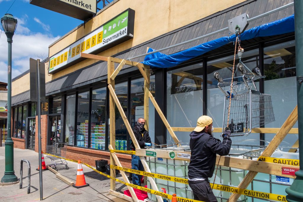 Small Supermarket employees disinfecting shopping carts, Covid-19 Virus response and social distancing, Philadelphia, Pennsylvania