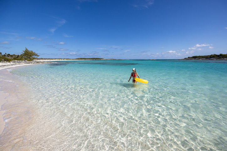 A woman floating on a yellow swim ring in the emerald waters, Exuma, Bahamas