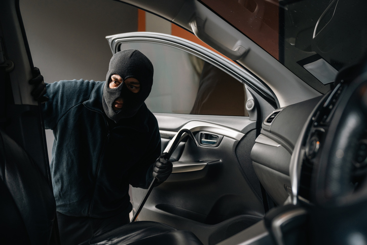 Thief in uniform black jacket various action stolen cars. The Robber terrorism criminal car with balaclava and crowbar breaking into a car window