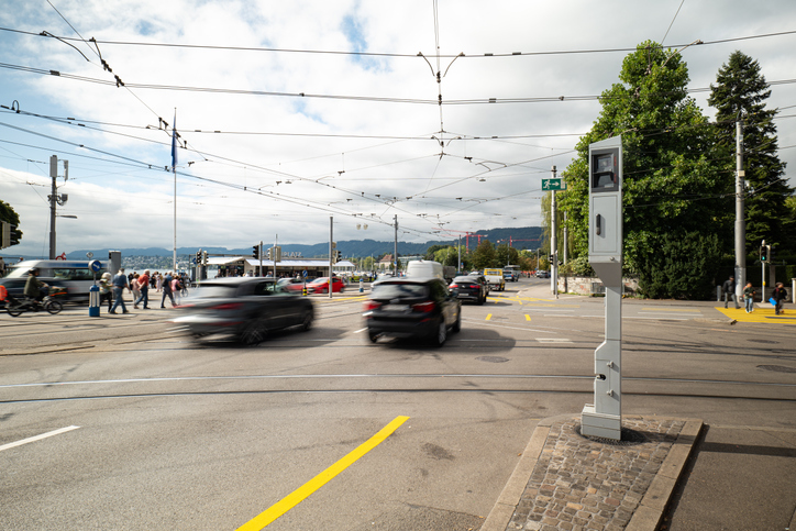 Blurred cars in traffic driving past a radar speed trap camera in a city in Europe