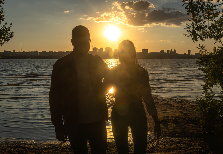 Couple walking by the waterfront at golden sunset