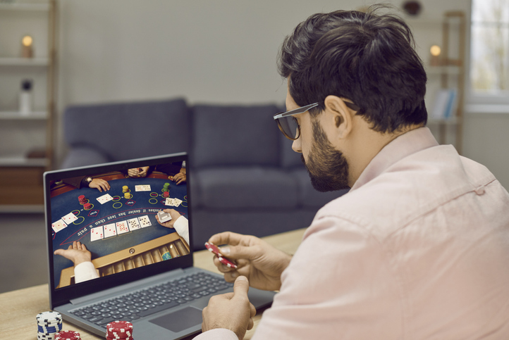 Young gambling man takes part in online poker tournament while relaxing at home.